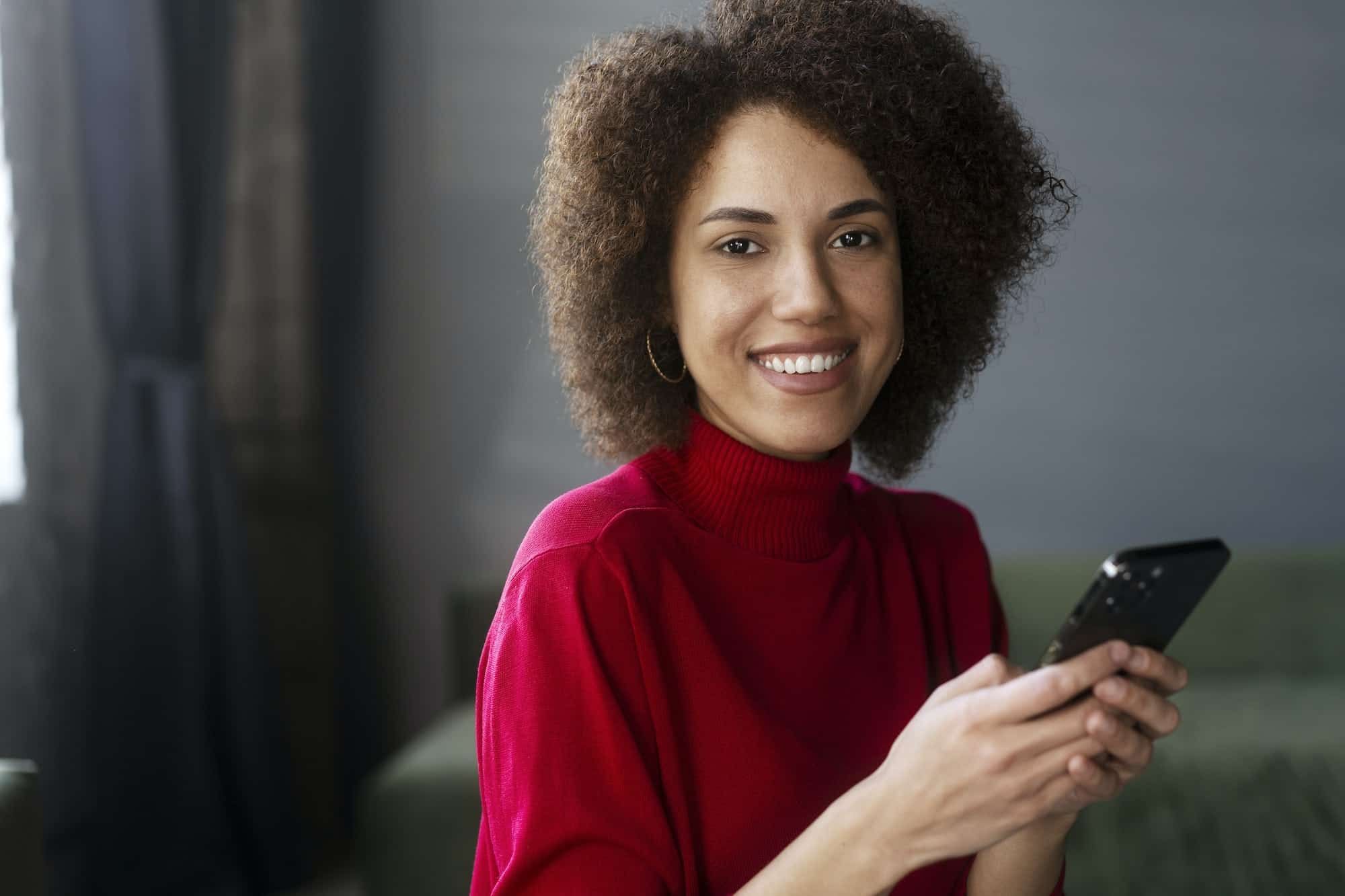 Portfolio 1 african american woman in red casual attire using mobile phone working online text messaging